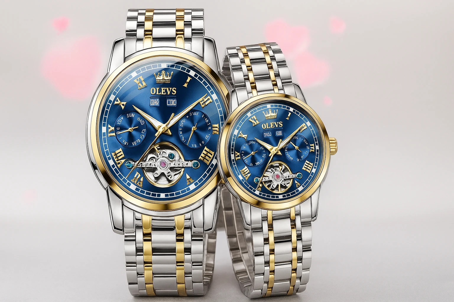 A pair of matching OLEVS luxury wristwatches with blue dials, gold Roman numerals, and silver-gold metal bands, set against a soft gray background with faint pink heart patterns.