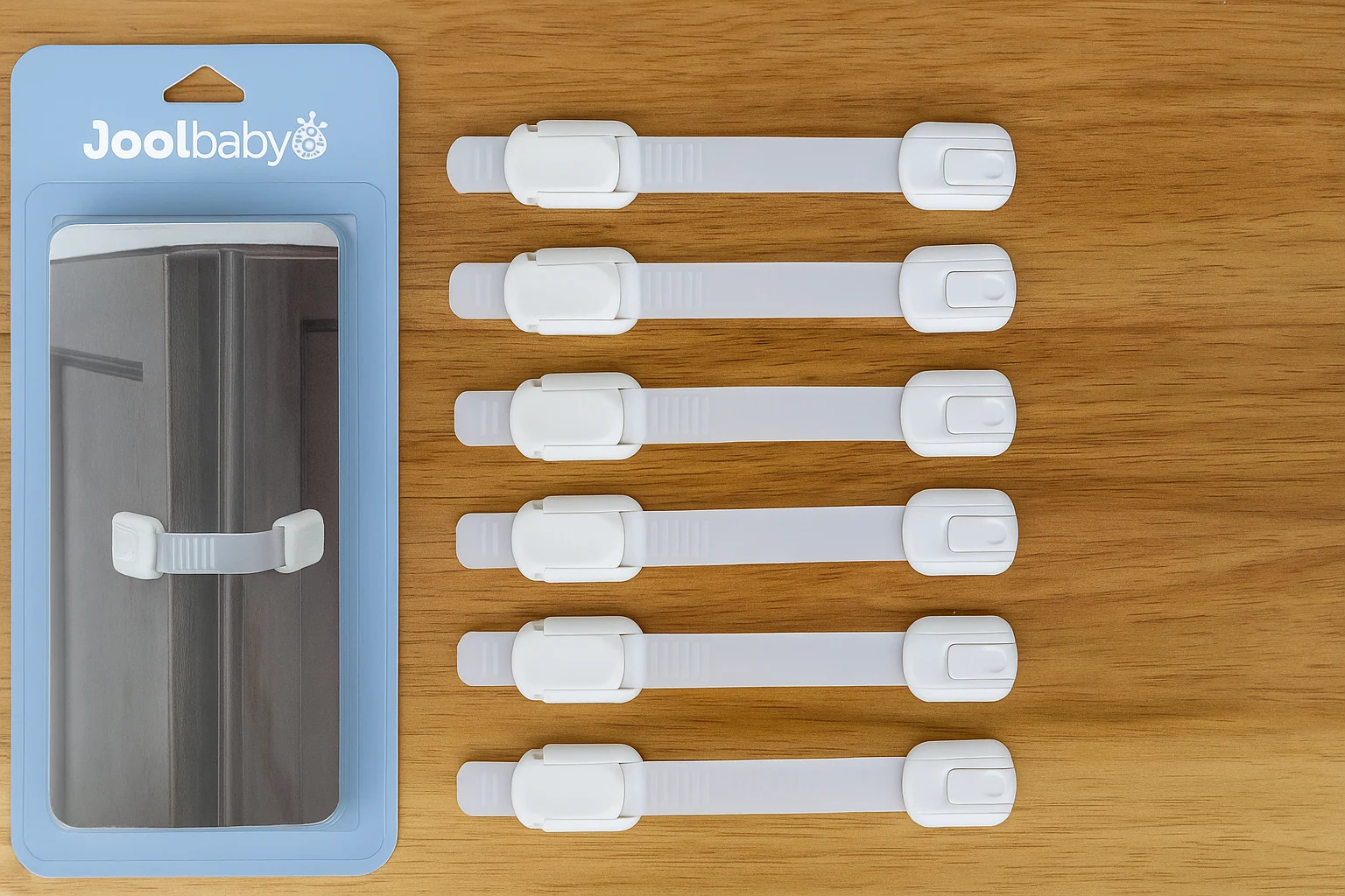 A digital photograph showcases eight white child safety strap locks by Jool Baby Essentials, neatly arranged on a wooden surface with a blue product package on the left.